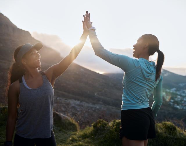 2 personen die elkaar een high five geven met een mooi uitzicht op de achtergrond